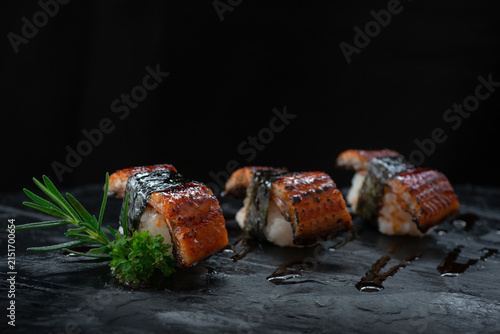 Japanese sushi with grilled eel topping is beautifully arranged on a black stone tray. Traditional Japanese culinary concept.