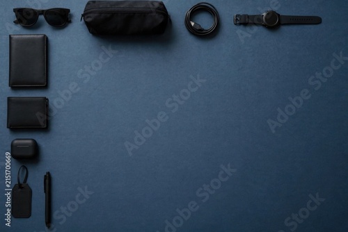 Flat lay of mens accessories arranged on a dark blue background.