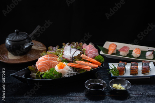 Sushi and sashimi set consisting of salmon, shrimp, octopus, eel and various sauces and seasonings is beautifully arranged on the table, a traditional Japanese culinary concept.