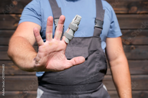 Canvastavla Man in workwear holding injured finger with splint, workplace accident and occup