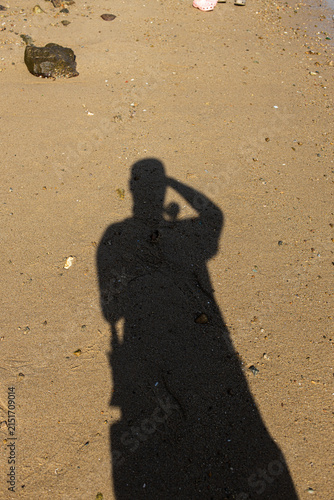 Shadow of a person standing on sandy beach during daytime