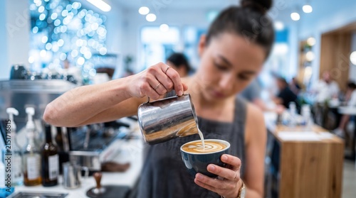 Professional barista crafting a perfect latte art design in a busy cafe during the holiday season