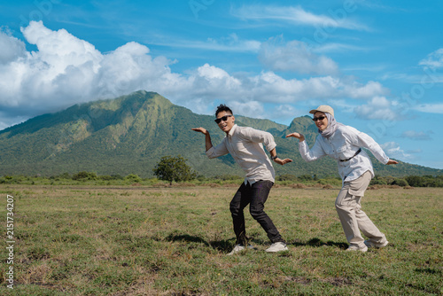 Happy Young Couple Enjoying Outdoor Adventure in Front of Scenic Mount Baluran Landscape