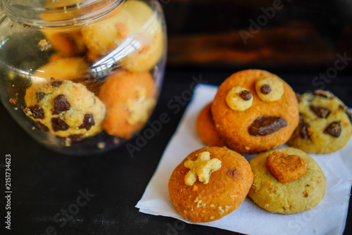 Obraz na płótnie Close-up shot of creative handmade cookies with fun monster face, star, and heart toppings served on white baking paper next to a clear plastic cookie jar