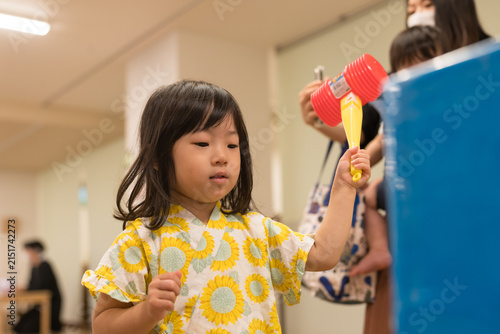 ひまわり柄の甚平を着ておもちゃのハンマーでゲームをする日本人の女の子の幼児