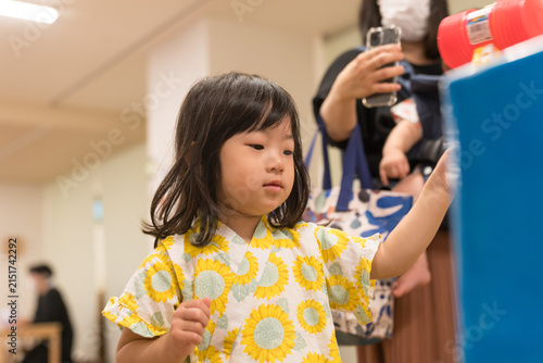 ひまわり柄の甚平を着ておもちゃのハンマーでゲームをする日本人の女の子の幼児