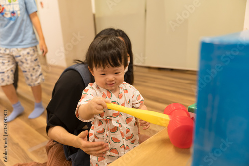 スイカ柄の甚平を着たおもちゃのハンマーで遊ぶ日本人の男の赤ちゃん