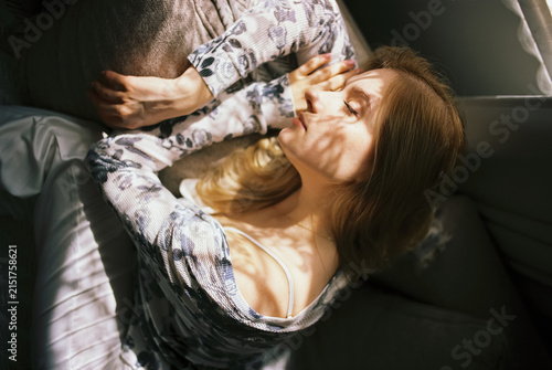 Young beautiful woman waking up in bed under sunlight, cozy home concept