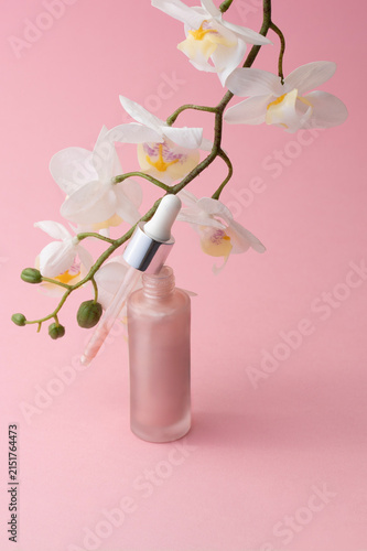 Open pink dropper bottle with orchid flowers, luxury skincare product visuals for advertising