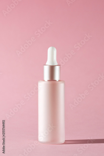 Pink dropper bottle on the pink background, luxury skincare product visuals for advertising
