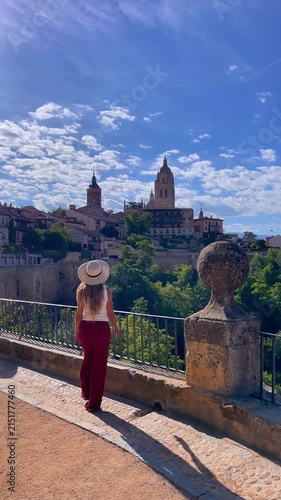 young woman wearing hat looking at segovia cathedral skyline spain