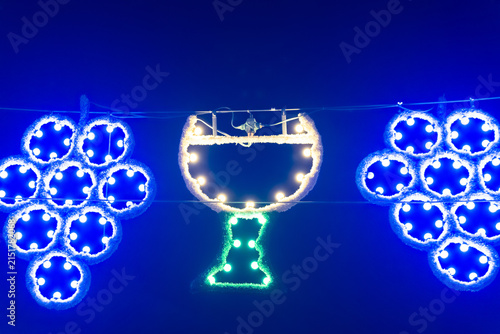Bright lights of grapes and a glass decorate a night scene during a local festival