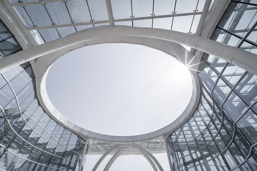 Fototapeta premium A modern architectural interior view of a circular skylight framed by glass and steel structures, showcasing sleek contemporary design.