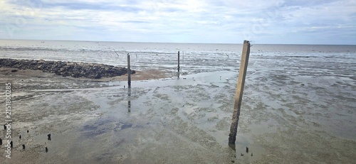 Concrete Mooring Posts and Rock Breakwater Wall at Low Tide, Small Boat Navigation Channel for Local Fishermen.