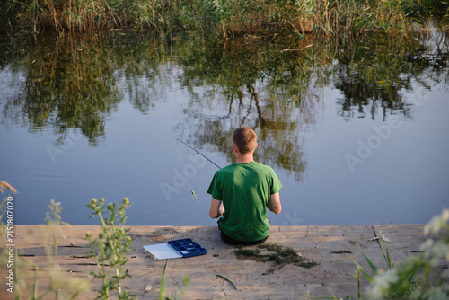 A fisherman sits on the pier with a fishing rod