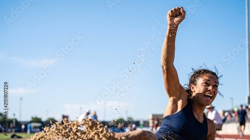Athlete landing from long jump celebrating in sandpit during competition