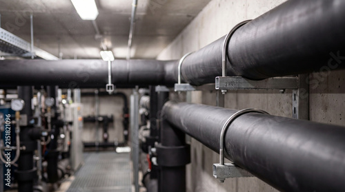 Comprehensive photograph showcasing large black insulated pipes running through a modern industrial facility ceiling.