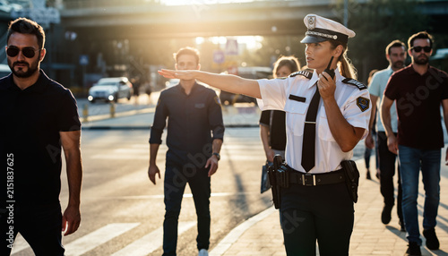Traffic officer directing pedestrians and vehicles at a crosswalk during sunset.
