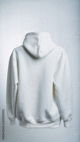 White hoodie with a hood, hanging against a plain background.