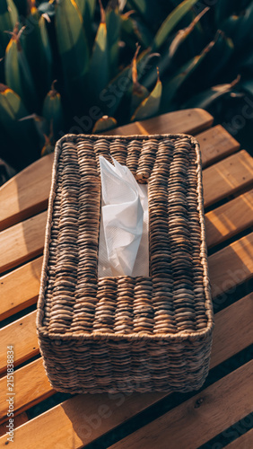 Wicker tissue box holder on wooden surface outdoors.