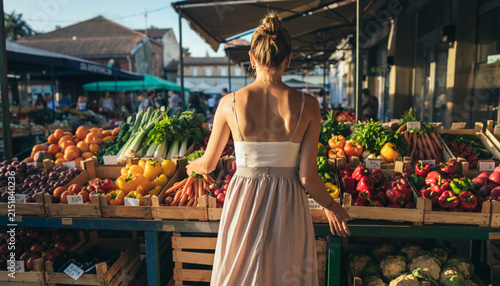 Woman shopping for fresh vegetables at outdoor market stall