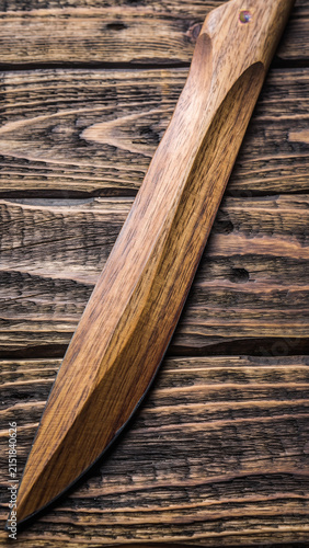 Wooden knife resting on weathered wooden surface.