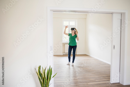 Woman in empty apartment wearing VR glasses