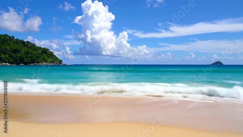 Tropical beach with turquoise water and lush green hills under a blue sky
