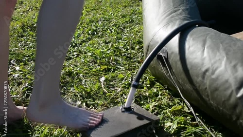 Woman inflating a rubber boat using a foot pump. Person standing barefoot on a floor pump to fill an inflatable raft with air for outdoor recreational water sport.