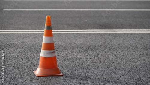 Orange traffic cone placed on asphalt road representing road maintenance, construction work, traffic safety and transportation infrastructure