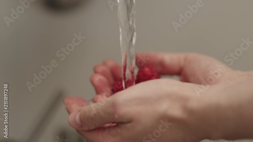 Slow motion man hand wash fresh ripe raspberries