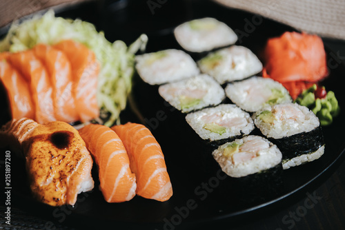 Photography Assorted sushi platter featuring salmon sashimi, maki rolls, and wasabi served o