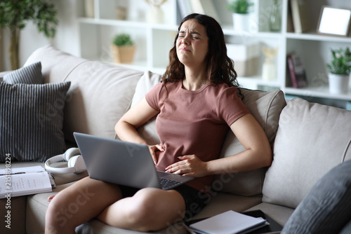 Obraz na płótnie Student suffering belly ache studying online at home