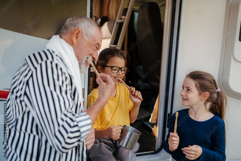 Fototapeta premium Granddad and girls brushing teeth. Morning routine during camper adventure.
