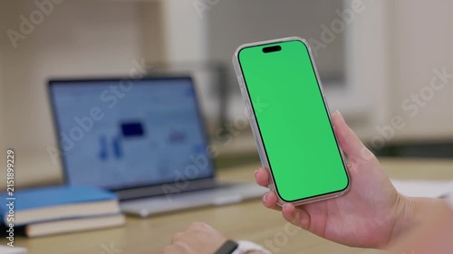 Close-up Of Smartphone With Green Mock-up Screen In Women's Hands On Desktop Background. Woman Using Mobile Phone, Browsing Internet, Social Networks, Financial Reports