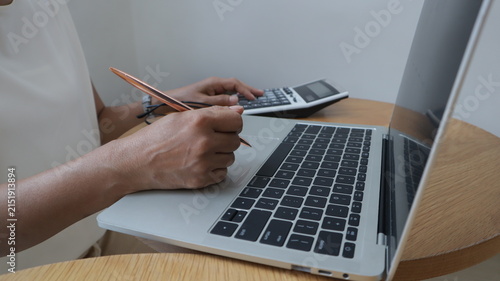 Professional business and financial planning concept featuring an entrepreneur working with a laptop, calculator, smartphone, and digital tablet at a wooden desk