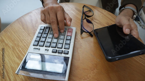 Professional business and financial planning concept featuring an entrepreneur working with a laptop, calculator, smartphone, and digital tablet at a wooden desk