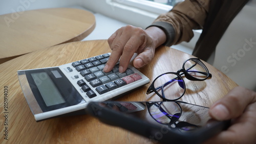 Professional business and financial planning concept featuring an entrepreneur working with a laptop, calculator, smartphone, and digital tablet at a wooden desk
