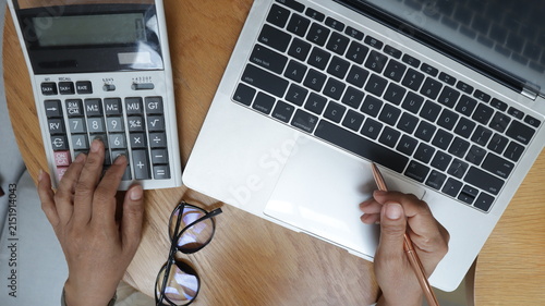 Professional business and financial planning concept featuring an entrepreneur working with a laptop, calculator, smartphone, and digital tablet at a wooden desk