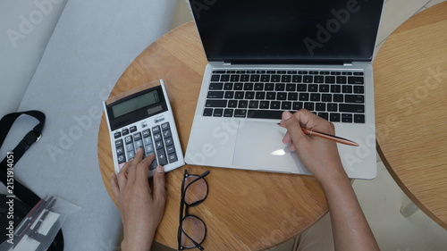 Professional business and financial planning concept featuring an entrepreneur working with a laptop, calculator, smartphone, and digital tablet at a wooden desk
