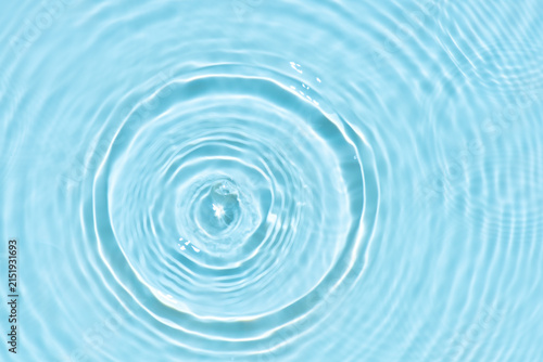 Blue water with ripples on the surface. Defocus blurred transparent white colored clear calm water surface texture with splashes and bubbles. Water waves with shining pattern texture background.