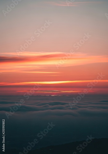 Vibrant Sunset Over Calm Ocean Horizon with Streaks of Orange and Pink Light.