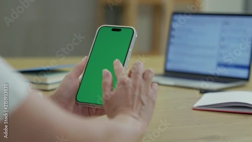 Woman Using Smartphone with Green Screen Chroma Key at Her Desk in Office. Woman Using Mobile Phone, Browsing Internet, Social Networks, Financial Reports