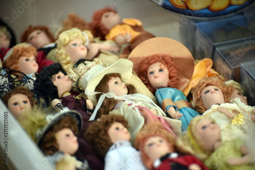 Collection of small retro dolls lying among vintage objects at a flea market, creating a nostalgic scene filled with childhood memories and collectible toys.
