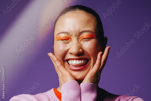 Asian woman with bold makeup smiling joyfully in a studio portrait
