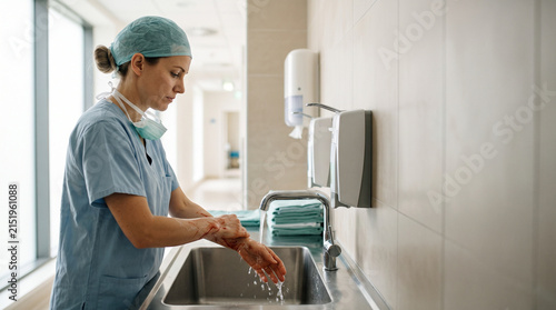 Doctor washing bloody hands in hospital restroom with surgical attire  