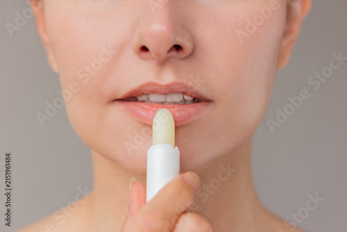 Bild auf Leinwand Close up of young woman face applying hygienic white moisturizing lip balm to her lips