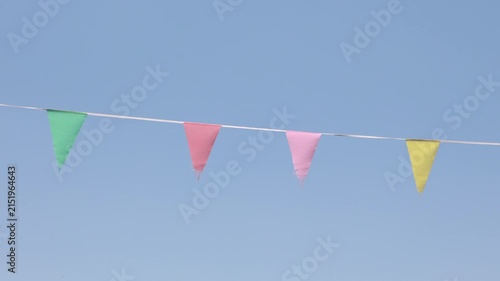 Colorful party pennants blowing in wind against clear blue sky