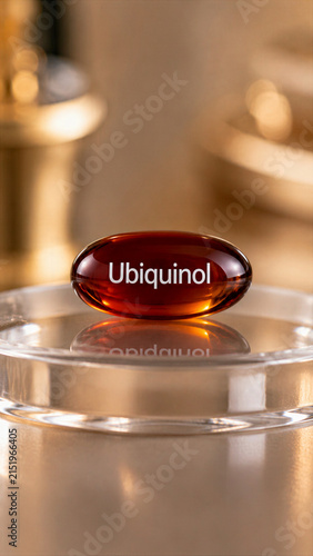 A gel capsule labeled Ubiquinol sits on a clear surface. The background includes blurred items that look like gold or metallic objects. This scene suggests a focus on health supplements
