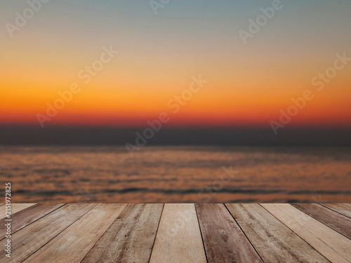 Wood table top over sunset beach with blurry sky background.
